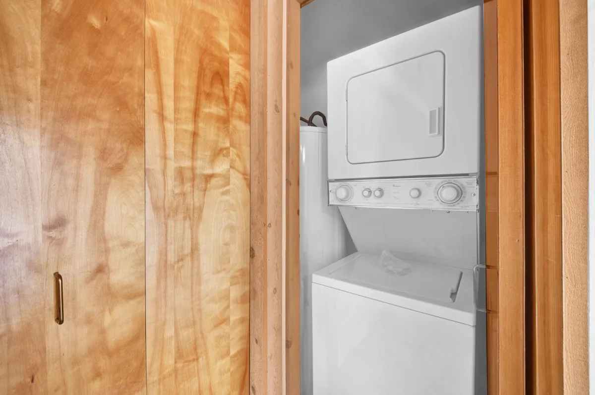 A practical laundry closet equipped with a washing machine and dryer, set against warm wooden cabinetry. The space is organized and functional, ideal for handling daily laundry needs during a stay.