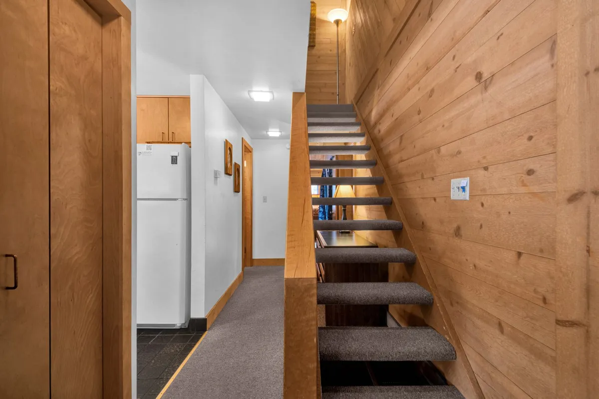 A staircase framed by wood paneling and inviting doorways, suggesting access to upper interior spaces. The scene signals transitions between levels and evokes the journey to the more adventurous sleeping nook above.