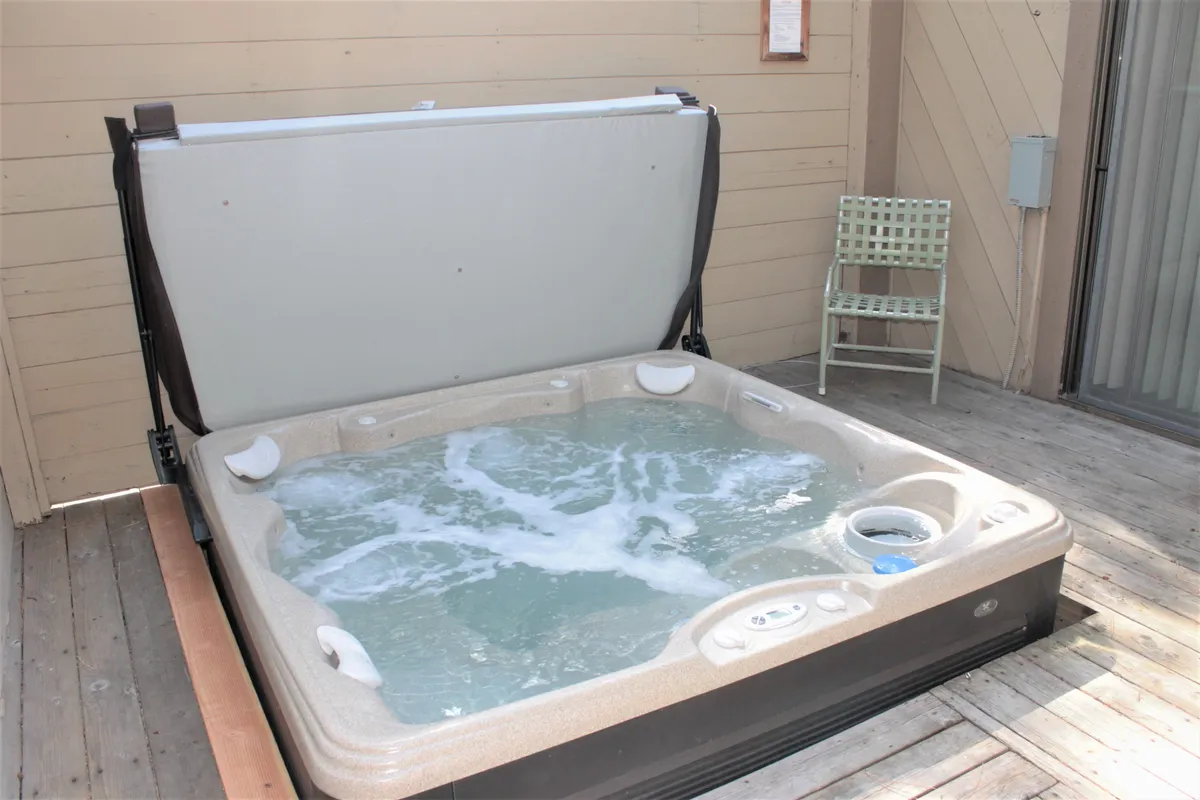 An exterior view of the hot tub on the deck, accompanied by a chair, with open sky above—setting the scene for sunset soaks or evenings under the stars, and subtly hinting at the golf course views mentioned in the section.